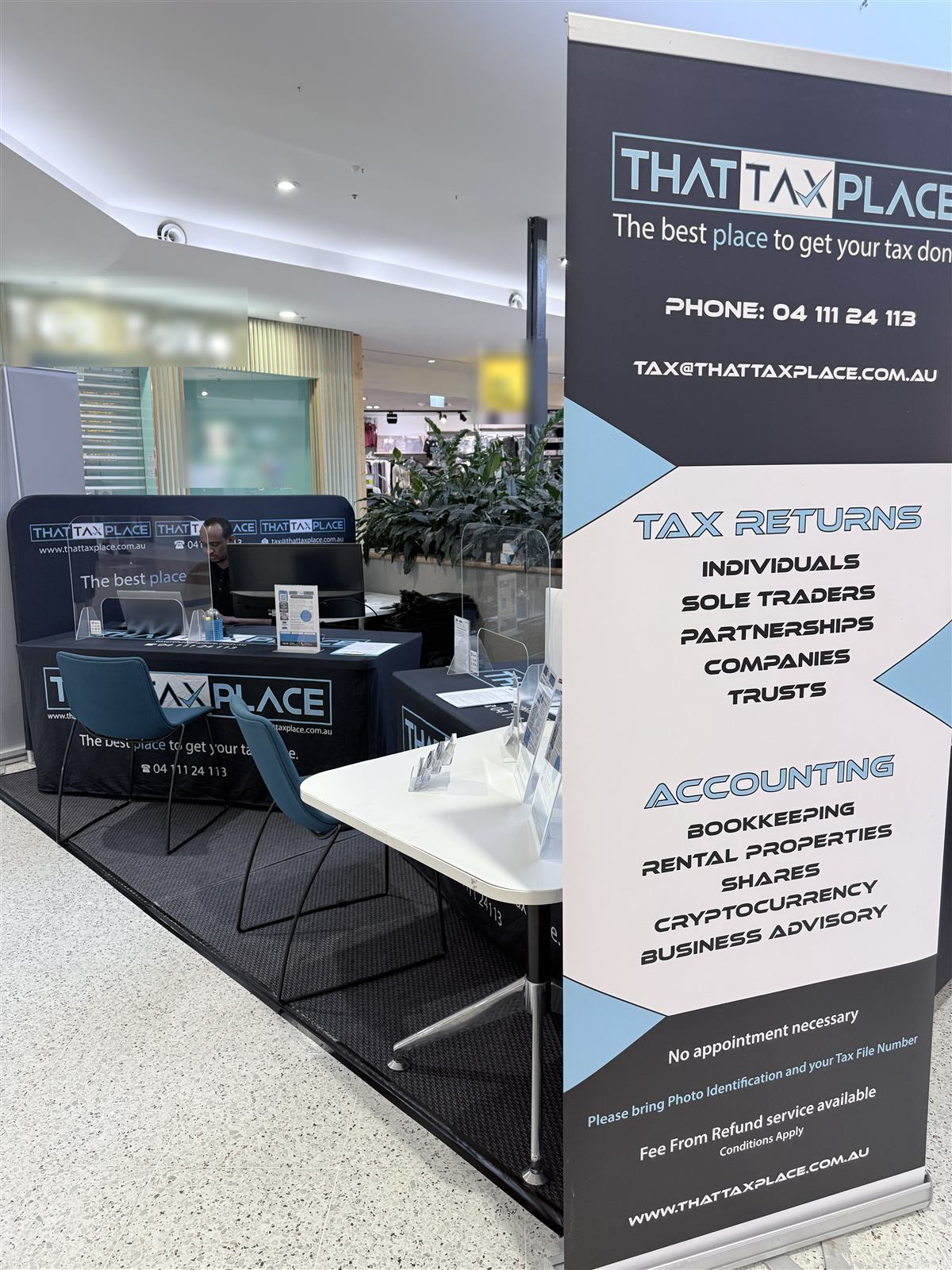 That Tax Place kiosk desks and a pull-up banner listing tax return and accounting services